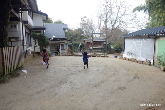 園庭で凧揚げをする子どもたち