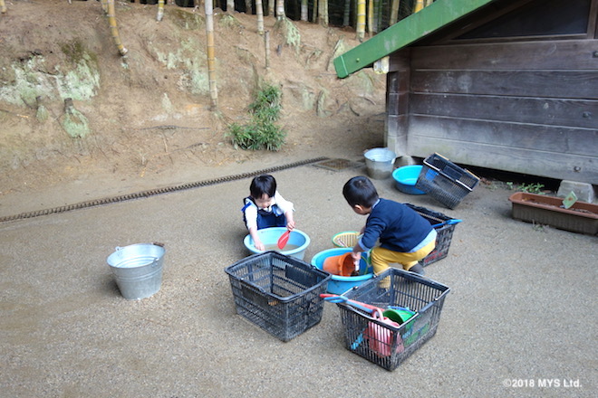 砂場で遊んだ道具を洗う子たち
