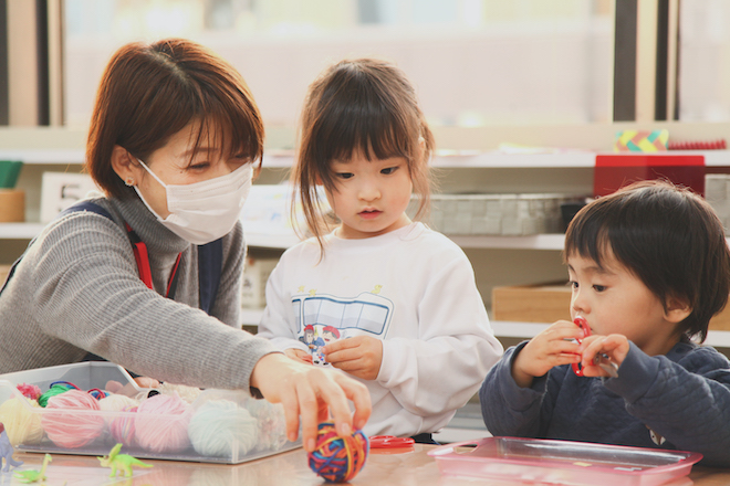 女性が持つカラフルな毛糸玉を見る男の子と女の子